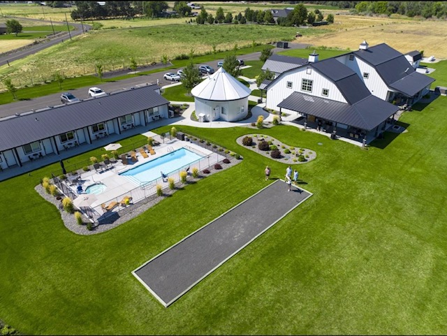 A drone photo showing the whole property: 6 rooms in a row, the standalone silo suite, outdoor pool, hot tub and main barn dining room building