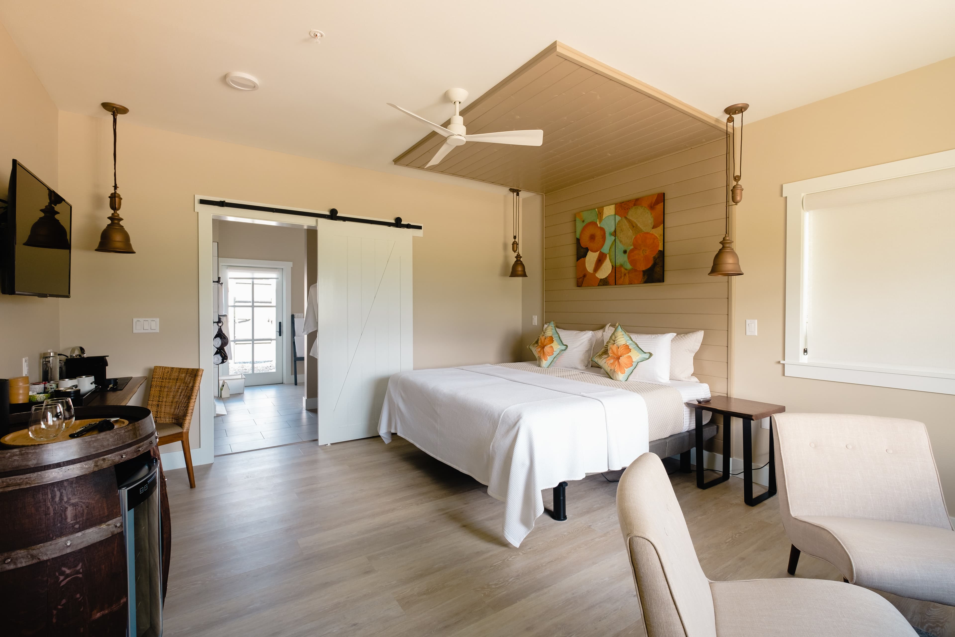 Interior view of the Barrel Suite showing beds, sitting area, entrance to bathroom. Warm colors